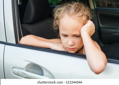 Sad Little Girl Sitting In The Car Near The Window