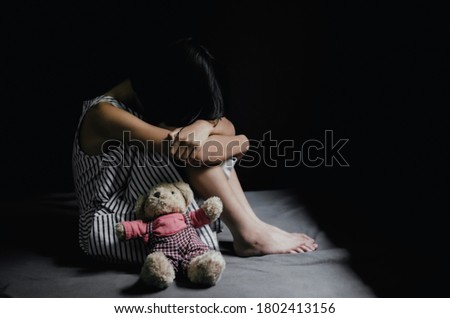 Sad little girl sitting in dark room. 