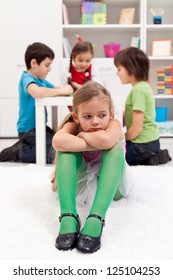 Sad Little Girl Sitting Excluded By The Other Kids