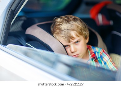 Sad Little Kid Boy Sitting In Car In Traffic Jam During Going For Summer Vacation With His Parents. Tired, Exhausted Child Not Happy About Journey.