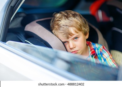 Sad Little Kid Boy Sitting In Car In Traffic Jam During Going For Summer Vacation With His Parents. Tired, Exhausted Child Not Happy About Journey.