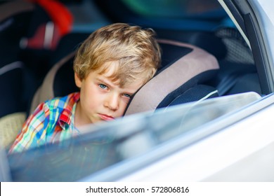 Sad Little Kid Boy Sitting In Car In Traffic Jam During Going For Summer Vacation With His Parents. Tired, Exhausted Child Not Happy About Journey.