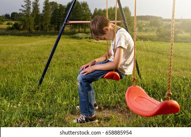 Sad Lonely Boy Sitting On Swing Alone