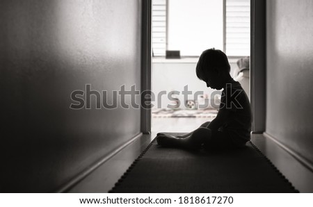 Sad and lonely little boy sitting on the floor. 