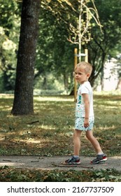 A Sad Lonely Little Boy Walks In A City Park. The Child Got Lost He Was Looking For His Parents.