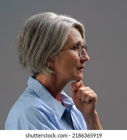 Sad Lonely Mature Woman. Senior Woman Thinking In Low Light. Grey Haired Mature Woman Studio Shot In Low Light. Dramatic Portrait Of An Mature Grey Haired Woman.