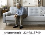 Sad lonely old grey haired man sitting alone on home sofa, looking down in bad thought, suffering from depression, apathy, coping with loss, bad news about healthcare, family problems