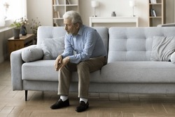 Sad Lonely Old Grey Haired Man Sitting Alone On Home Sofa, Looking Down In Bad Thought, Suffering From Depression, Apathy, Coping With Loss, Bad News About Healthcare, Family Problems