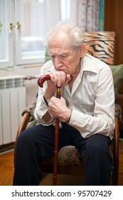 Sad Lonely Old Man Sitting In An Armchair With His Cane