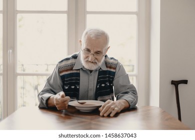 Sad Lonely Senior Man Eating Soup In Empty Apartment