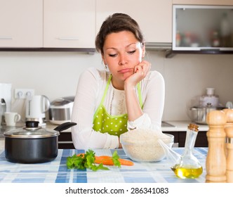 Sad lonely woman cooking rice in the kitchen 