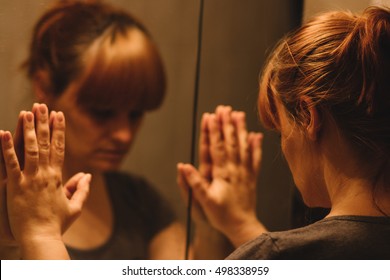 Sad And Lonely Woman Looking At Her Reflection In The Mirror