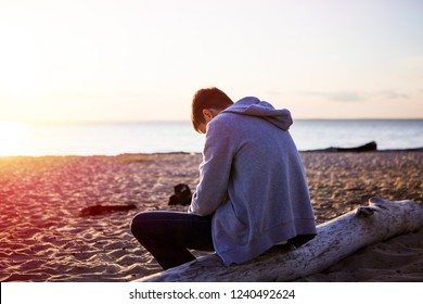 Trauriger und einsamer junger Mann sitzen am Meer