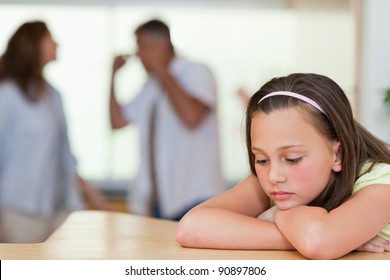 Sad looking girl with her fighting parents behind her - Powered by Shutterstock