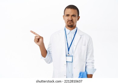 Sad Male Doctor, Therapist Pointing Ad Looking Left With Upset, Unhappy Face Expression, Standing Over White Background