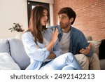 Sad man asking sorry to upset woman both sitting on the sofa at home. Discussion between man and woman about jealousy and relationship problems. Breakup marriage divorce concept. Guilty husband cheat