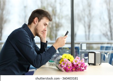 Sad Man With A Bouquet Of Flowers Stood Up In A Date Checking Phone Messages In A Coffee Shop