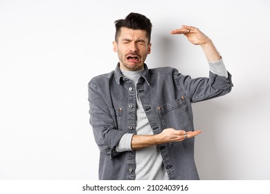 Sad Man Crying And Showing Big Size Object, Shaping Large Thing And Complaining, Sobbing While Standing On White Background