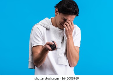 Sad Man Crying While Watching Tv With Remote Controller, Isolated On Blue