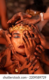 Sad Man Faces Covered Up By A Lot Of Hands With Henna Tattoos While Wearing A Gold Crown On Her Head