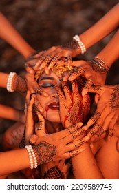 Sad Man Faces Covered Up By A Lot Of Hands With Henna Tattoos While Wearing A Gold Crown On Her Head