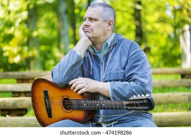 Sad man with  guitar in park on bench
