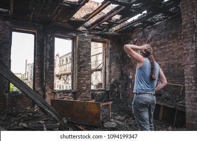 Sad Man Holds His Head By Hand And Cry In Burnt Out House After Disaster. Loss And Despair Concept, Consequences Of Fire