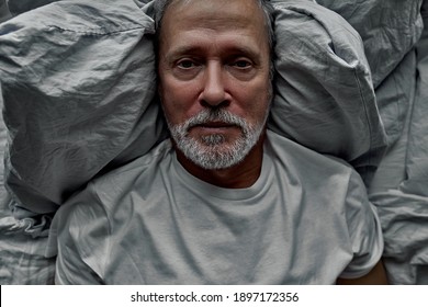 sad man lie on bed alone looking at camera, suffering from loneliness, no meaning in life