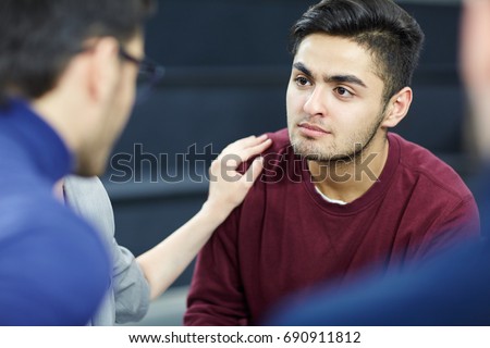 Sad man listening to advice of colleague during group session
