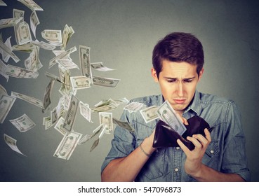Sad man looking at his wallet with money dollar banknotes flying out away  - Shutterstock ID 547096873