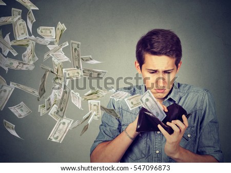 Sad man looking at his wallet with money dollar banknotes flying out away 
