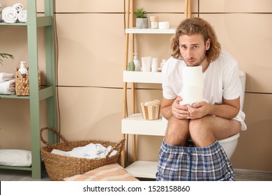 Sad Man With Paper Sitting On Toilet Bowl At Home