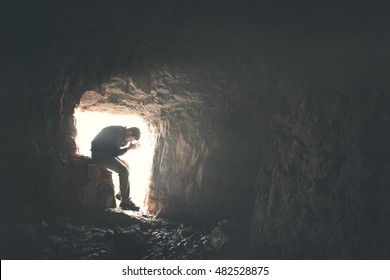 sad man praying god in a dark cavern 