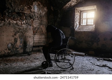 Sad man sitting in old wheelchair in abandoned hospital ward. Person silhouette in decayed vehicle for disabled patients in old building. - Powered by Shutterstock