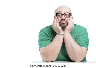 Sad Man Sitting At The Table. Studio Photography On A White Background.