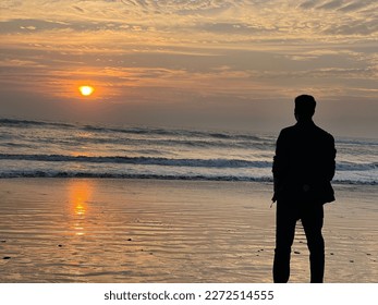 A sad man standing standing in front of sea beach. Dark shadow and vintage look. The time is Evening. Golden rays of sun is gleaming on all over the beach. Sad and emotional man looking at the beach.  - Powered by Shutterstock