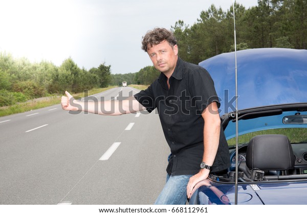 Sad man thumb a lift calling for assistance after\
breaking down on the road