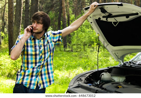 A sad man is waiting for help and\
calling the support service because his car broke\
down