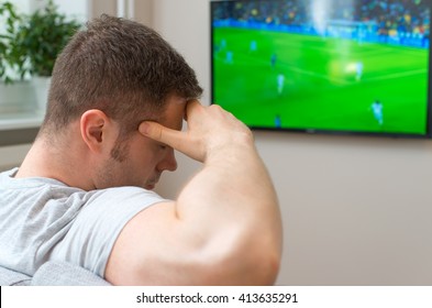 Sad Man Watching Football Match On Television At Home.