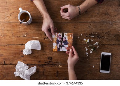 Sad Mans, Womans Hands Holding Torn Picture Of Romantic Couple. 