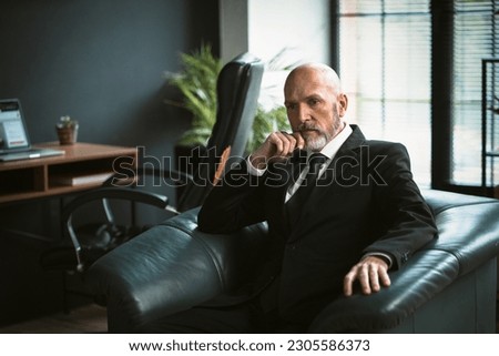 Sad mature man dressed in suit, sitting in chair, deep in thought. Essence of his introspection and contemplation, highlighting his profound wisdom and business acumen. . High quality photo