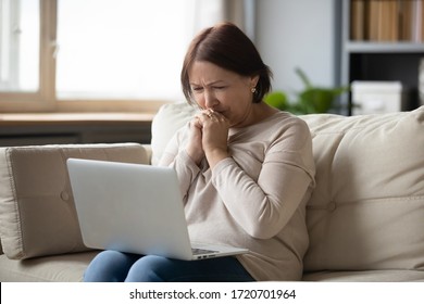 Sad Mature Woman Looking At Laptop Screen And Crying, Sitting On Couch At Home, Unhappy Older Female Using Computer, Reading Bad News, Debt Or Bankruptcy, Watching Movie, Making Video Call