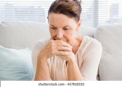 Sad Mature Woman Sitting On Sofa At Home