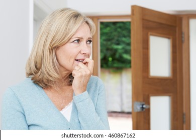 Sad Mature Woman Suffering From Agoraphobia Looking Out Of Open Door