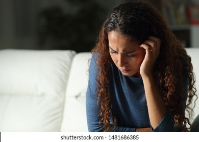 Sad mixed race woman complaining sitting on a couch in the living room at home