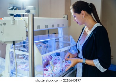 Sad Mother Looking At Her Newborn Baby In An Incubator In Hospital. Phototherapy Treatment To Reduce Bilirubin Levels In Newborn Jaundice.