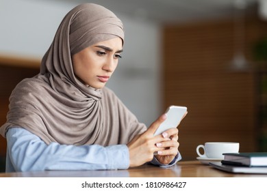 Sad Muslim Girl Holding Mobile Phone, Cafe Interior, Empty Space