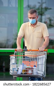 Sad Old Man With Face Mask Leaving A Super Market With A Shopping Cart - Selective Focus On The Man
