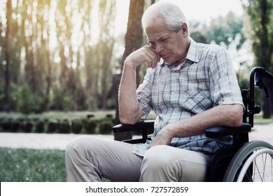 Sad Old Man In A Wheelchair Pensively Sitting In Summer Park