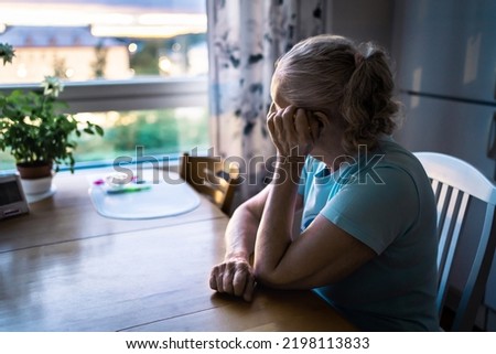 Sad old woman. Depressed lonely senior lady with alzheimer, dementia, memory loss or loneliness. Elder person looking out the home window. Sick patient with disorder. Pensive grandma. Widow with grief